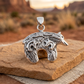 Textured silver bear pendant on sandstone with a softly blurred Southwestern desert backdrop.